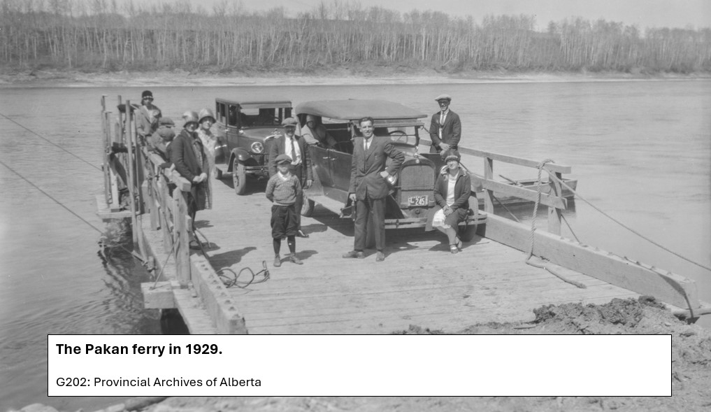 Flat raft like ferry with 2 old cars and people dressed well. Photo taken in 1927.