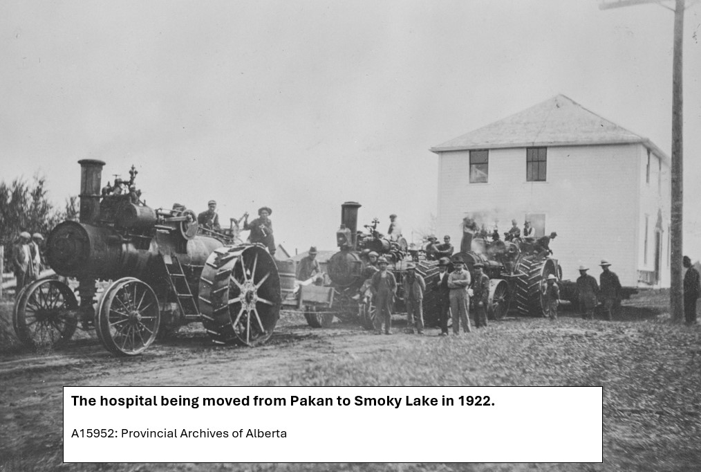 2 story building being pulled by 3 steam tractors.