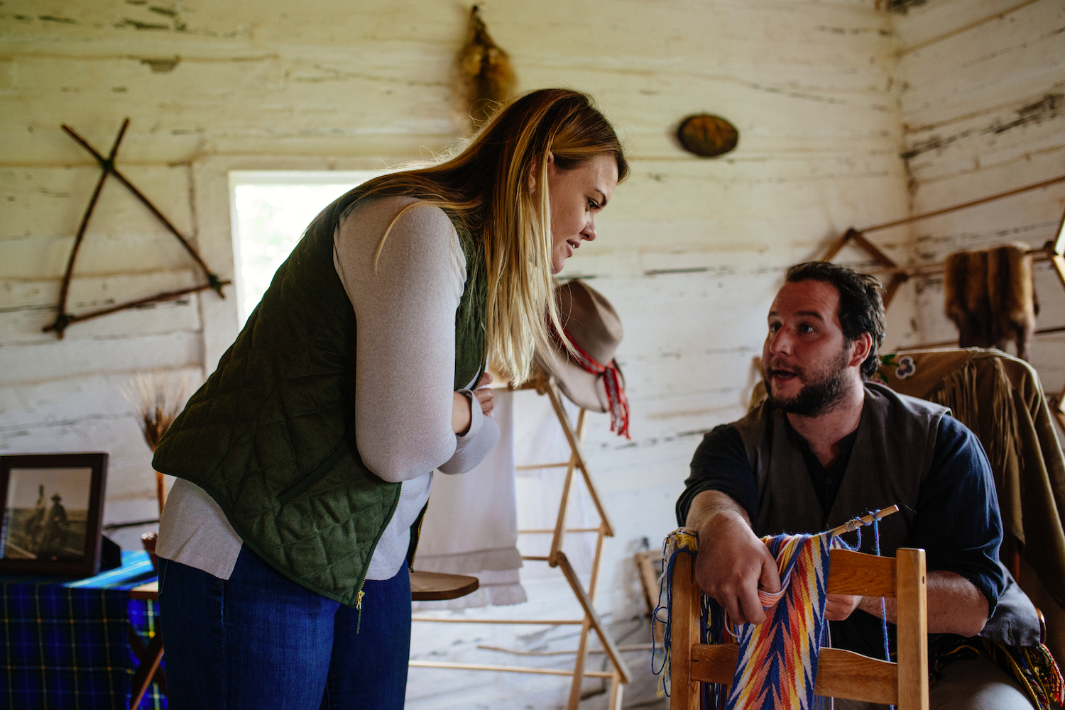 A visitor watches a man weaving a sash